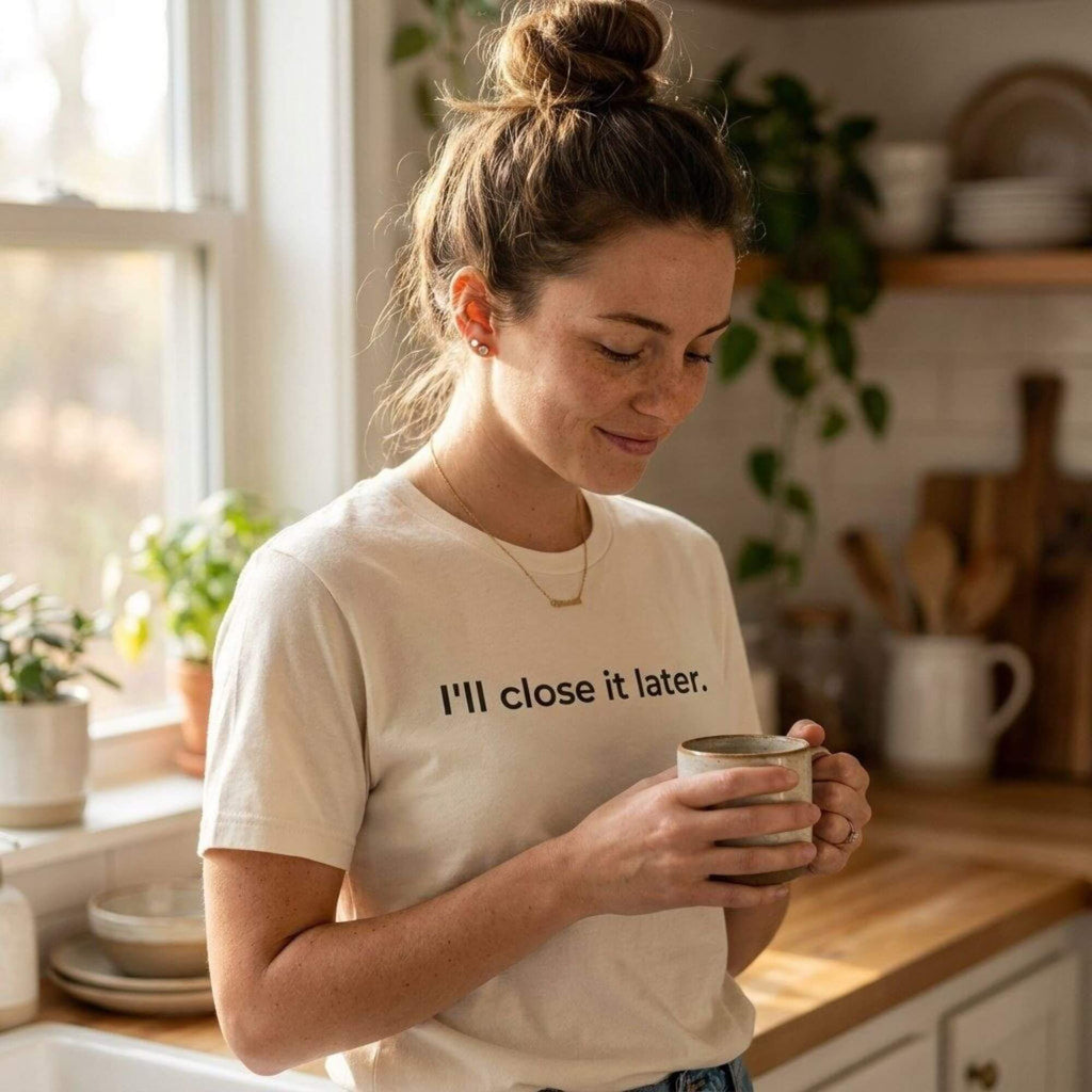 woman wearing i'll close it later natural white t-shirt holding coffee in kitchen — text & tone