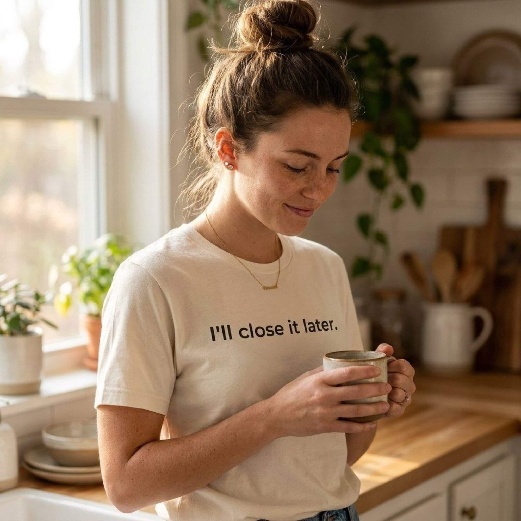 woman wearing i'll close it later natural white t-shirt holding coffee in kitchen — text & tone