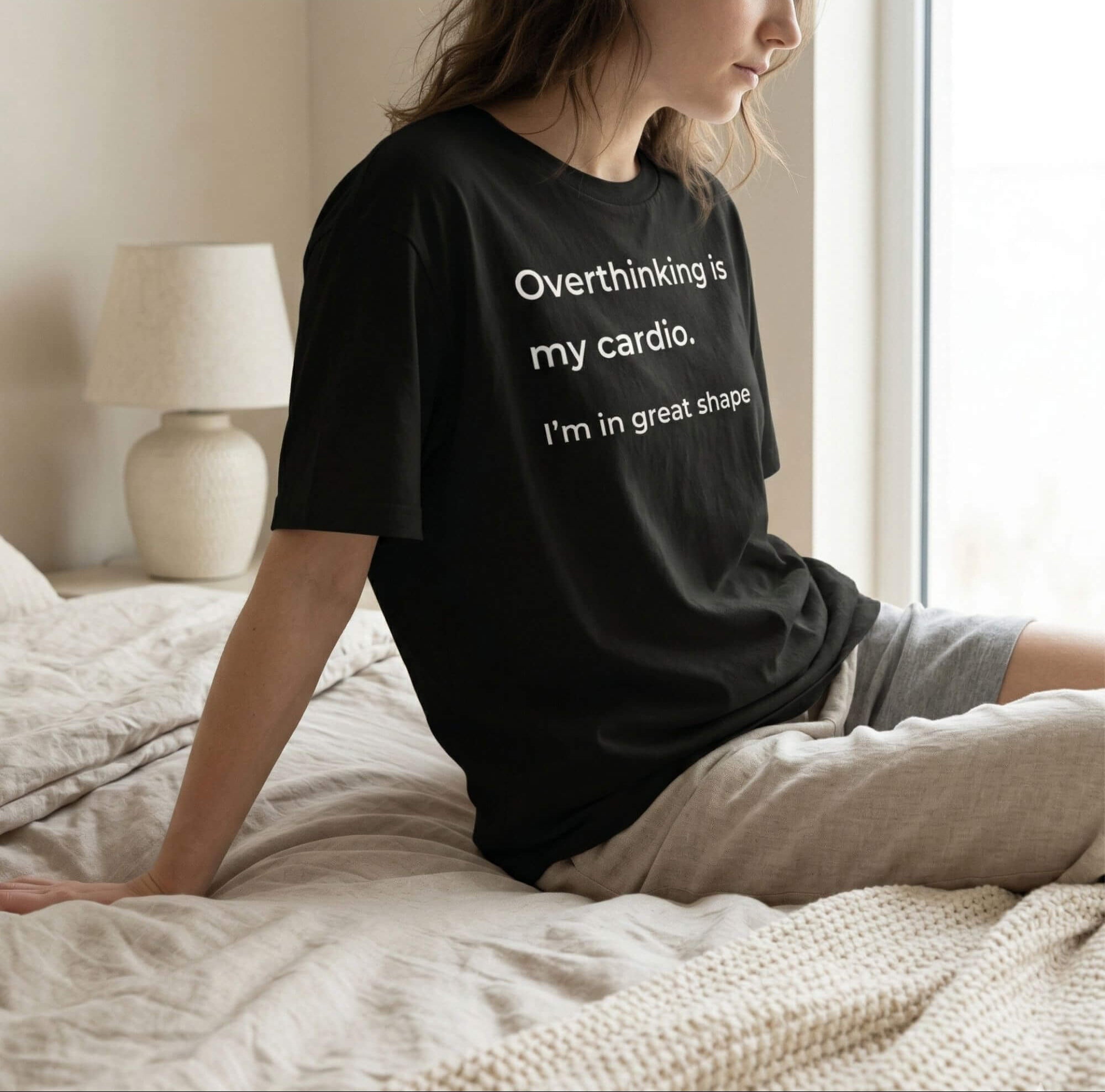Woman wearing black overthinking quote t-shirt in a calm bedroom setting