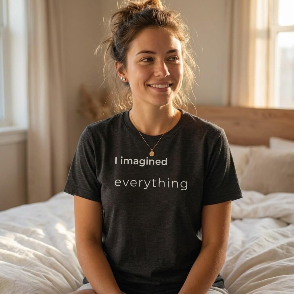 woman sitting on bed in i imagined everything charcoal slogan tee — text & tone