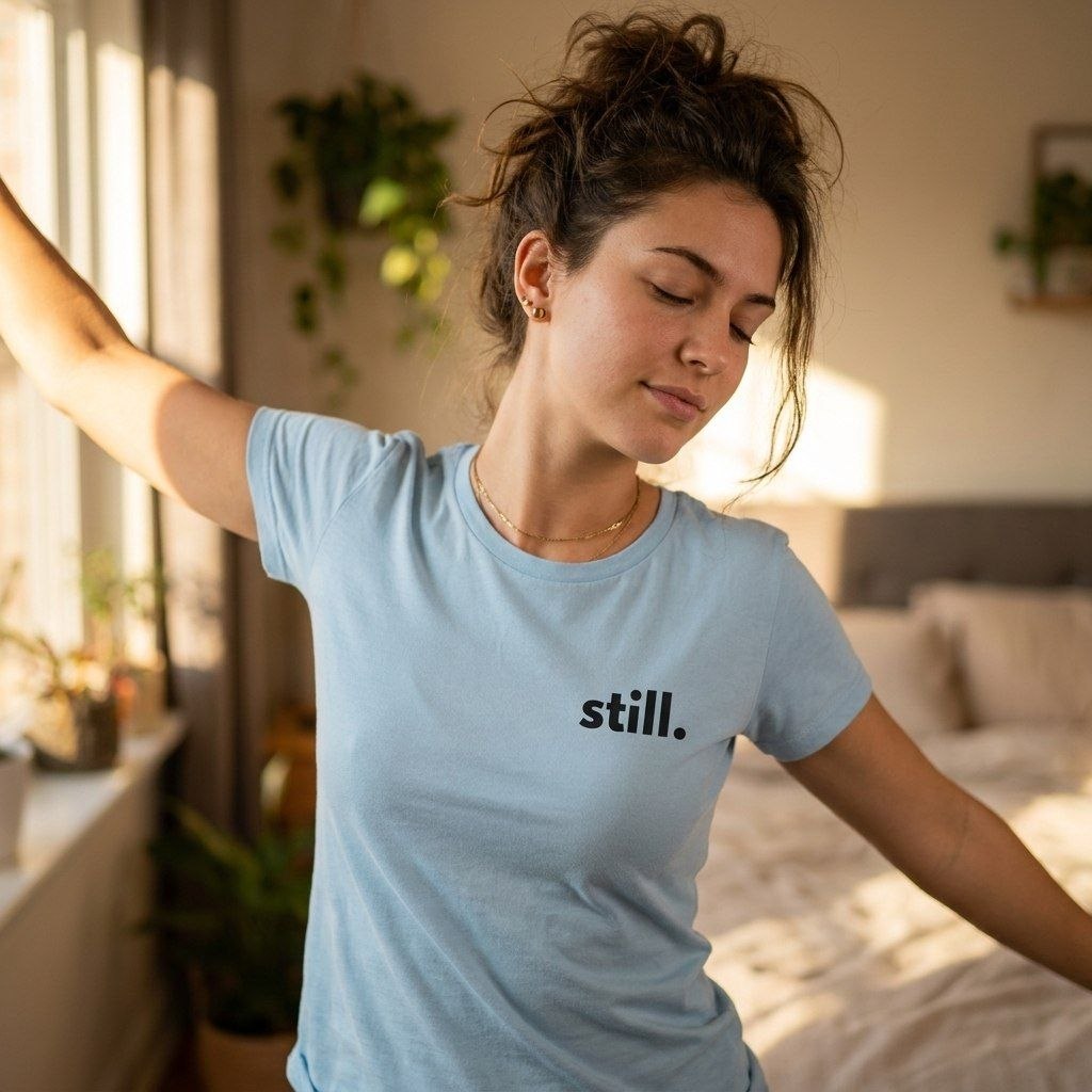 woman wearing still light blue minimalist t-shirt stretching — morning bedroom — text & tone