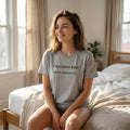 woman wearing i function best under mild panic grey t-shirt sitting on bed — text & tone