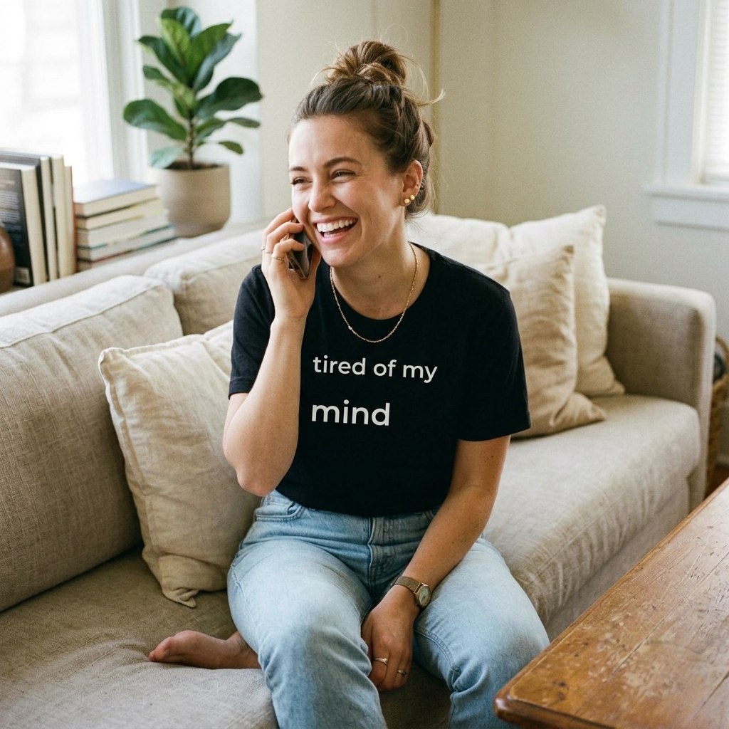 woman laughing on phone wearing tired of my mind black t-shirt on sofa — text & tone
